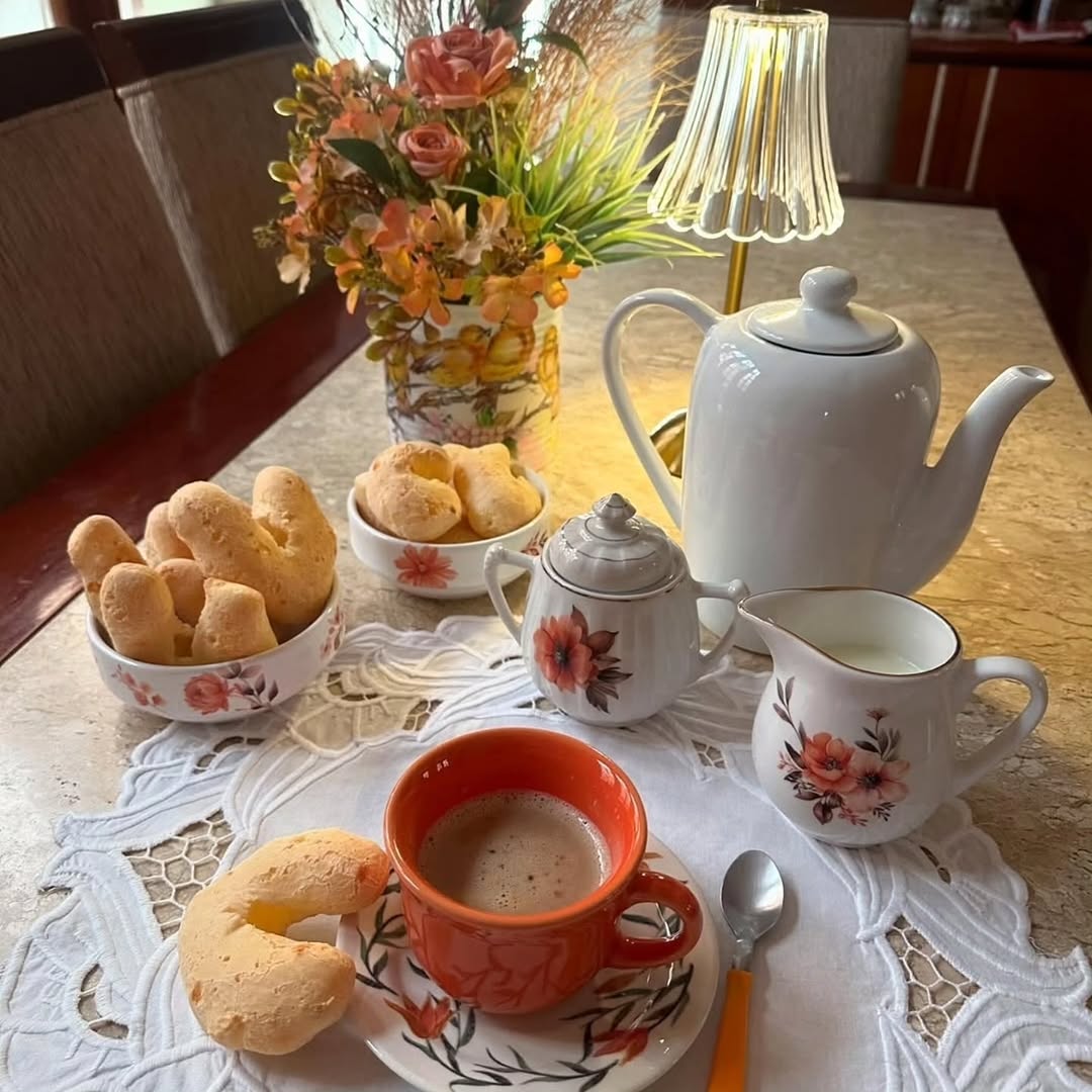 Numa manhã chuvosa, o som suave da água caindo trazia uma sensação de paz. O céu cinza deixava o ambiente mais acolhedor, e o aroma quentinho do pão de queijo preenchia a casa. Entre uma mordida e outra, o tempo parecia desacelerar, convidando ao descanso e à tranquilidade.